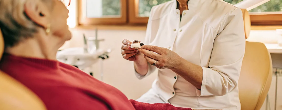Dental sleep medicine specialist showing a custom oral appliance to a patient during a consultation in a bright, modern clinic