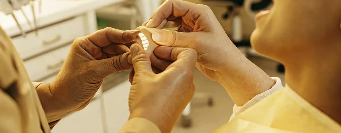 Dentist fitting a custom oral appliance for a sleep apnea patient in a clinical setting